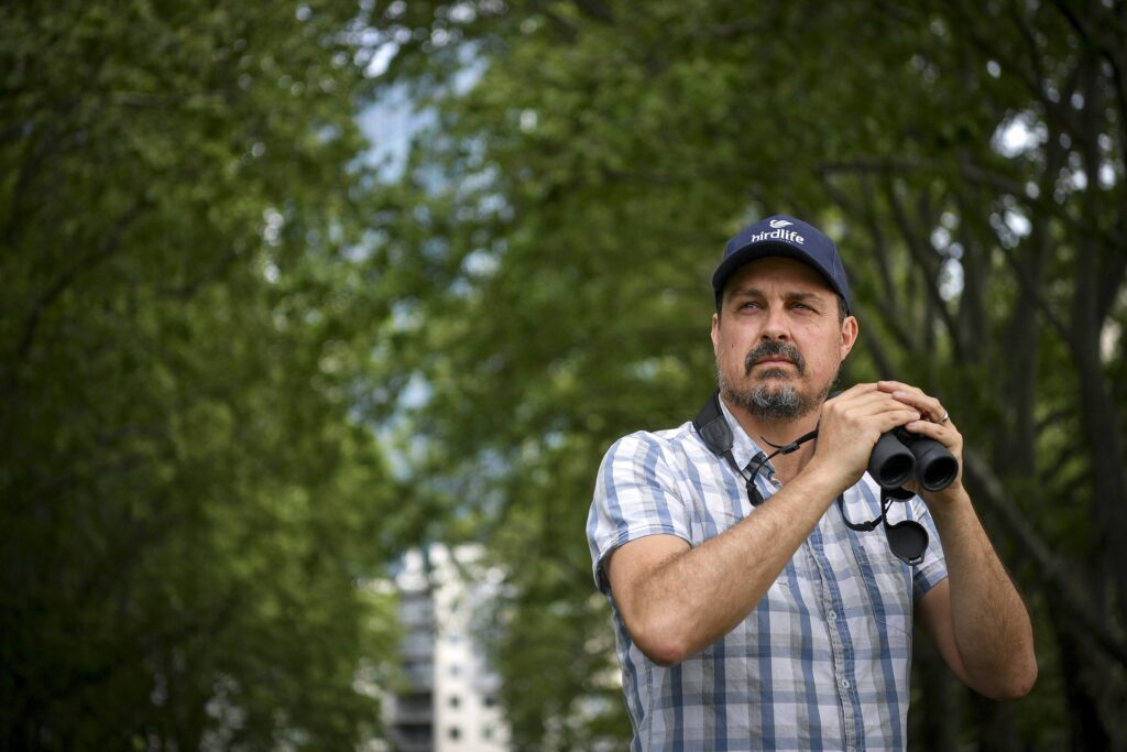 Sean Dooley of BirdLife Australia photographed outside on a bird walk with binoculars 